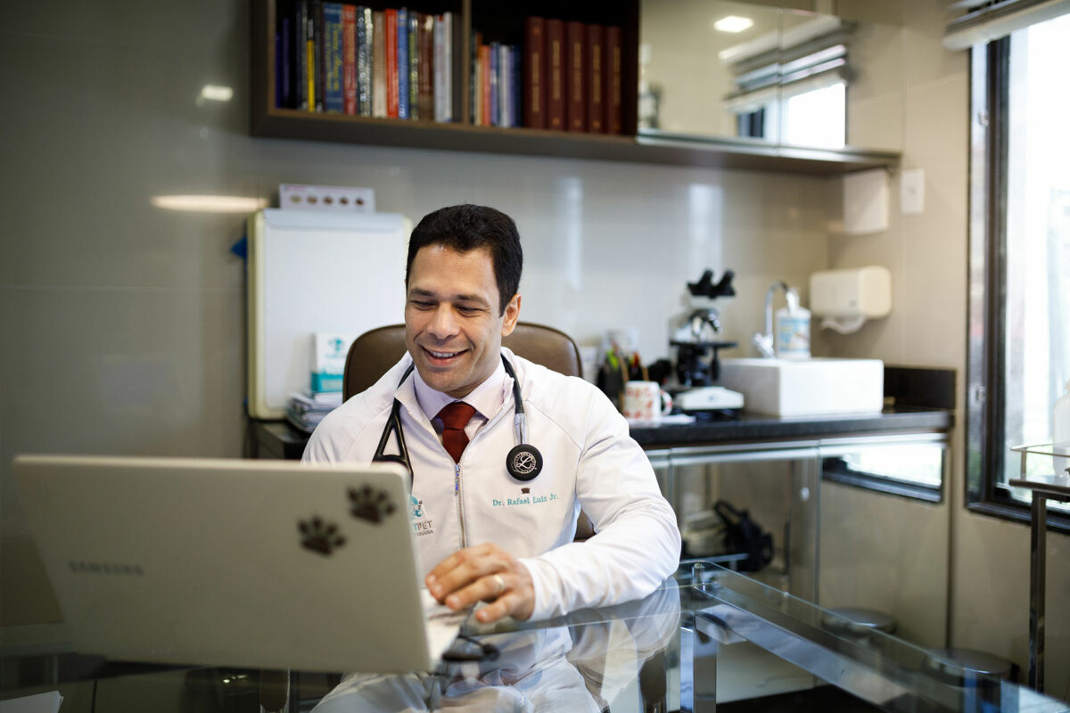 Médico veterinário sorri enquanto olha para o computador
